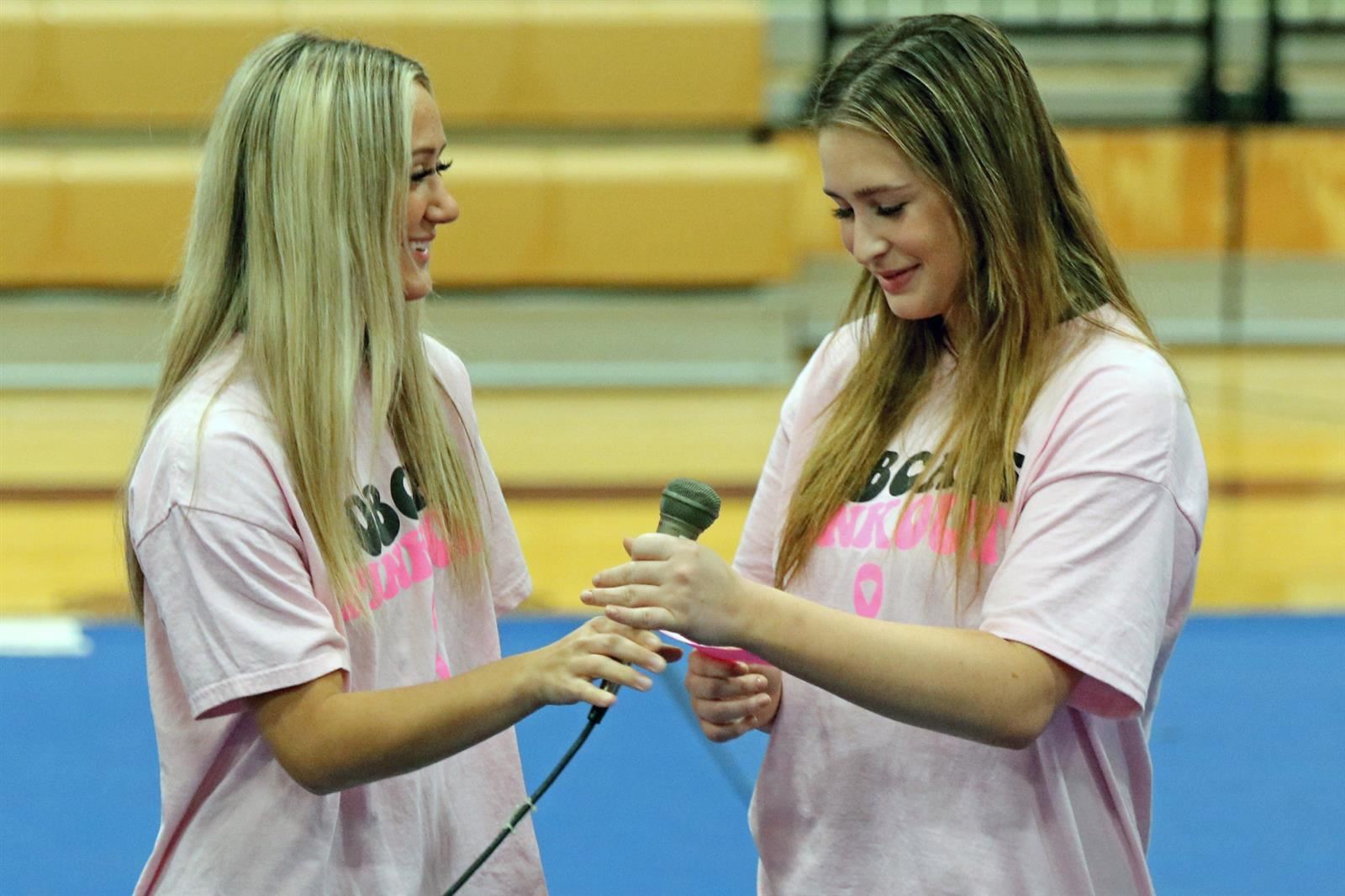 Cy-Fair High School volleyball players Emily Riley, left, and Isabella Torres read facts about breast cancer.